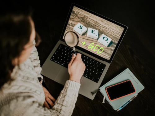 Frau mit Lupe vor Laptop, auf dem SEO + GEO steht